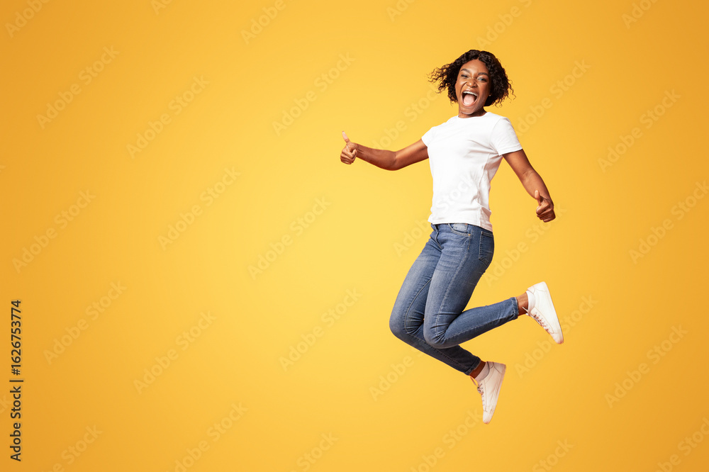 Definitely recommend it. Emotional young black woman jumping in the air and screaming, showing thumbs up, happy african american lady expressing positive emotions on orange studio background Definitely recommend it. Emotional young black woman jumping in the air and screaming, showing thumbs up, happy african american lady expressing positive emotions on orange studio background