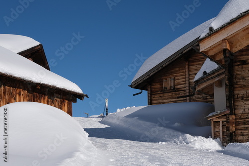 Snow-Covered Wooden Cabins Under Clear Blue Sky