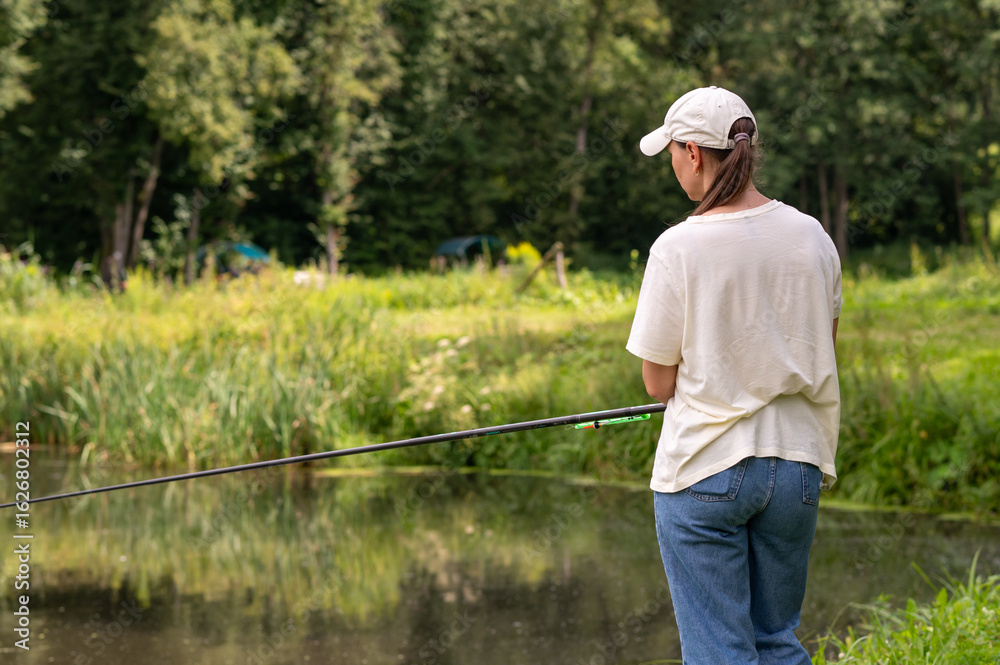 Woman fishing on a lake, rear view on peaceful summer day Woman fishing on a lake, rear view on peaceful summer day
