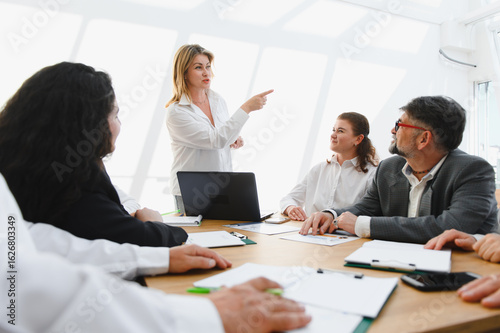 Business team meeting, leader explaining strategy and pointing towards success