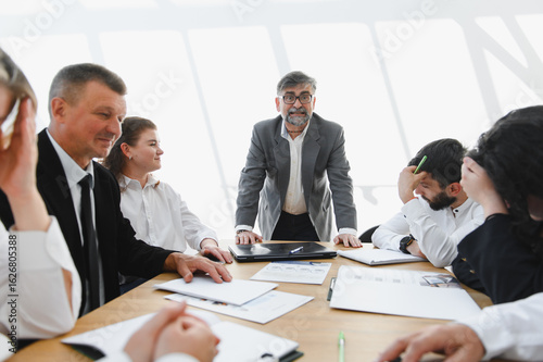 Fotografie Senior businessman leading a meeting with a discouraged team