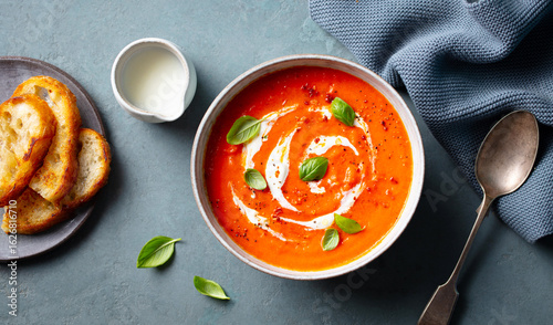 Foto Tomato soup with cream in a white bowl on grey background