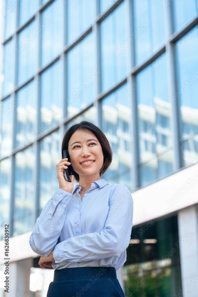 Eastern female ceo entrepreneur businesswoman working talking on smartphone cellphone. Asian mature business woman manager using cell phone for connection call standing outside at office. Vertical Eastern female ceo entrepreneur businesswoman working talking on smartphone cellphone. Asian mature business woman manager using cell phone for connection call standing outside at office. Vertical