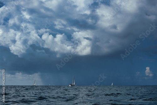 Sailing boats under dramatic stormy sky on open sea