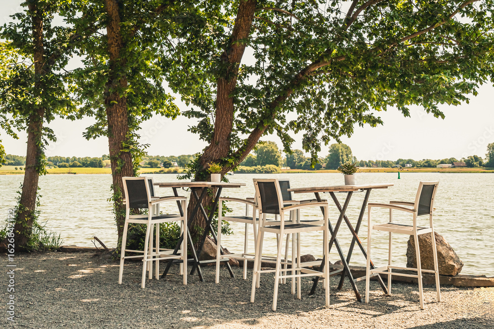 Obraz premium Bar stools and tables on the bank of a river