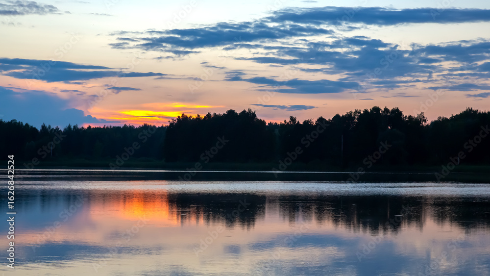 Fototapeta premium Sunset reflections over a tranquil lake surrounded by lush forests
