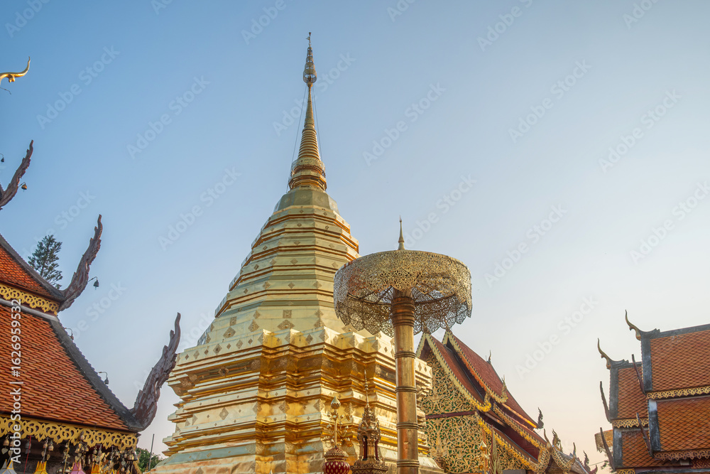 Fototapeta premium Golden stupa at Buddhist temple Wat Phra That Doi Suthep with ornate golden ceremonial umbrella at sunset in Chiang Mai, Thailand. Thai religious architecture. Travel and touristic landmark