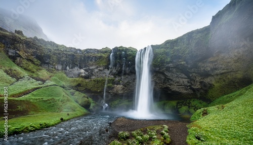 majestic waterfall cascading down a rocky cliff face surrounded by lush greenery and rolling hills a vast expanse of water plunges into a misty pool at the base of the falls