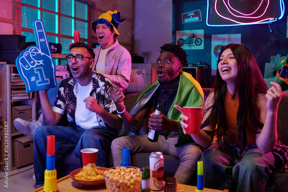 Obraz premium Group of multiethnic young adults cheering and celebrating while watching sports game on television, holding drinks and snacks, showing excitement and enthusiasm in living room setting