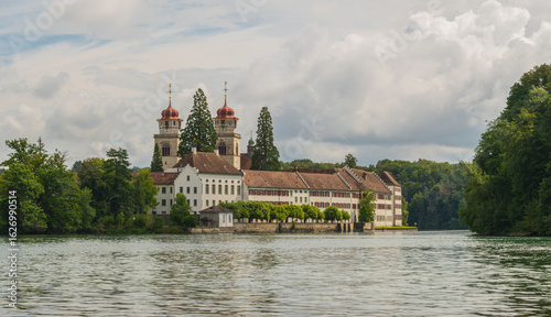Wallpaper Mural Historic castle situated by a serene lake under a cloudy sky surrounded by lush greenery Torontodigital.ca