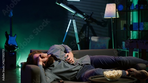 Man in apartment suffering heart attack while watching movie on TV, living troublesome sedentary lifestyle. Sick person feeling pain in chest, trembling on couch, fighting for his life, camera A