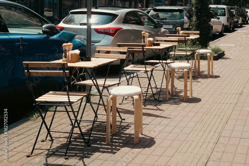 фотографія Wooden tables and chairs of a street cafe line the sunny sidewalk in Batumi, Georgia