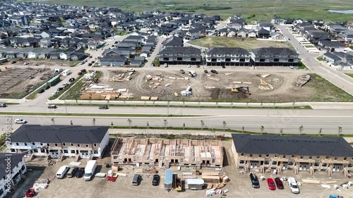 Residential area with a construction site in the middle. The houses are being built and there are many cars parked around the area