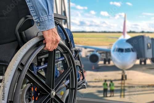 Person with disability in wheelchair before boarding flight at airport terminal window.