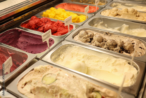 Variety of gourmet artisan craft organic gelato ice cream flavors in a shop cafe display case, creamy textures with caramel nuts chocolate, berry sorbet, colorful ice cream selection, dessert shop