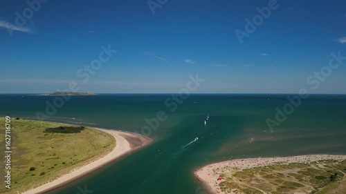 Drone zoom out with view of Malahide beach, Lambay Island and ships sailing out to sea