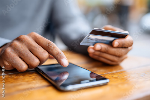 Man Using Smartphone to Make Online Payment With Credit Card in a Cafe Setting During Daytime