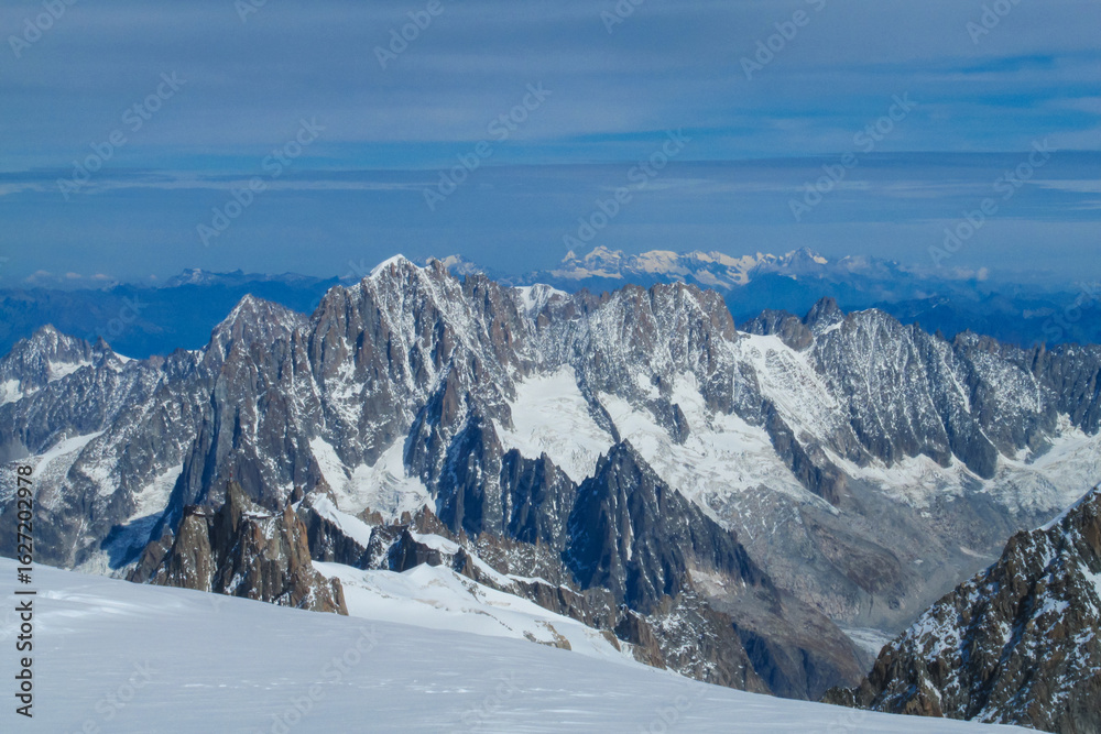 Fototapeta premium View of Aiguille du Midi summit from ascent route Gouter to Montblanc. Chamonix valley landscape of a prominent rocky towering mountain peak Aiguille du Midi in French Alps. Chamonix-Montblanc area