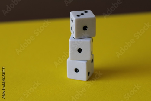 Una toma de cerca  de uno o varios dados blancos para juego en un fondo amarillo