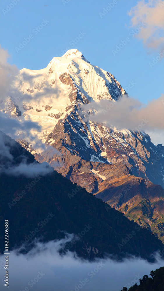 Obraz premium Majestic Mountain Peak: An awe-inspiring view of a snow-capped mountain rising boldly against a bright blue sky, embodying the raw power and beauty of nature.