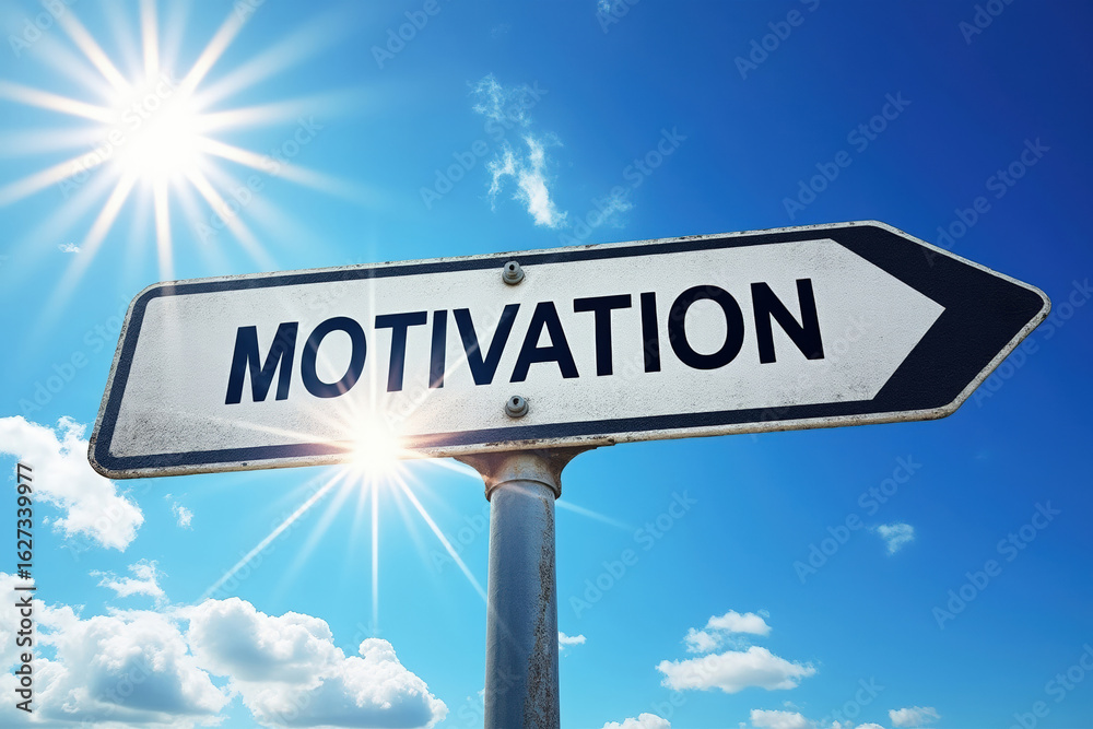 Fototapeta premium Directional Sign Pointing Towards Motivation Under a Bright Sun Against a Blue Sky Symbolizing Guidance and Inspiration for Achieving Goals