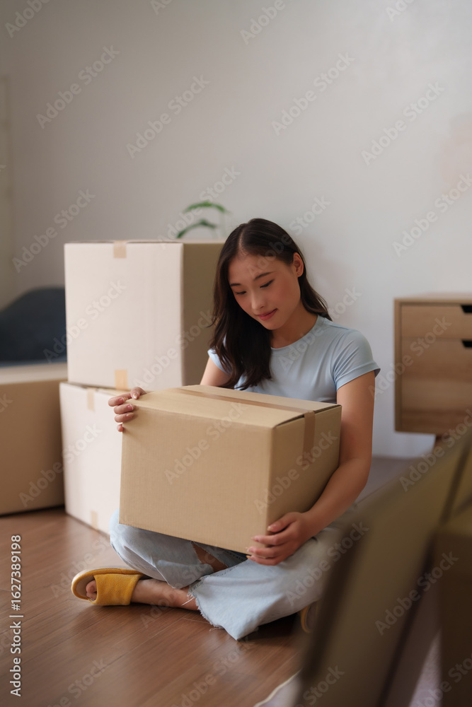 Asian adult woman carefully organizing packing moving boxes new home apartment relocation smooth transition personal space setup Asian adult woman carefully organizing packing moving boxes new home apartment relocation smooth transition personal space setup
