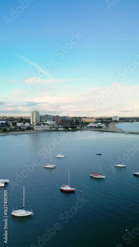 Aerial fly over boats in marina towards St Kilda bayside with blue sky