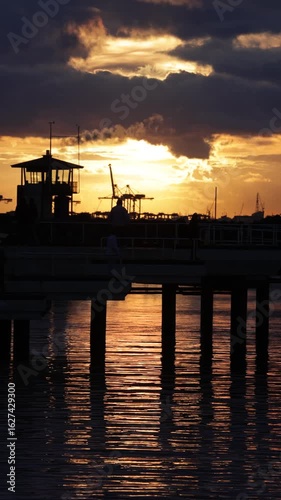 Slow motion of person walking on pier at sunset on pier in silhouette