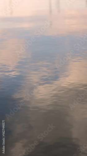 Calm water reflecting a pastel pink and blue sunset sky for background
