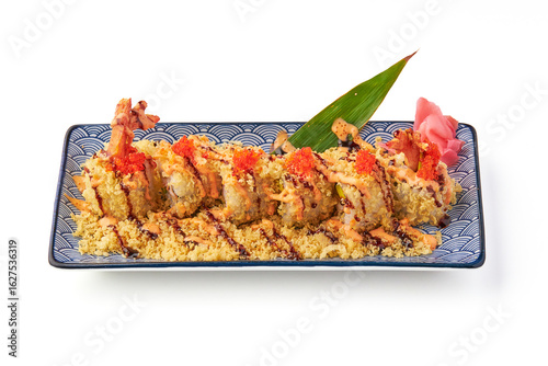 Crispy shrimp tempura sushi roll topped with spicy mayo, tobiko, and tempura flakes, served on decorative plate with pickled ginger and green leaf garnish