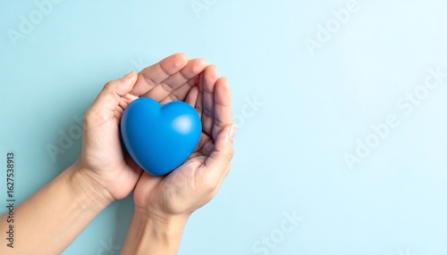 Hands holding a blue heart on a light blue background