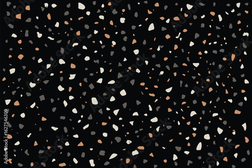 A dark background filled with small irregular shapes in shades of white gray and tan scattered randomly