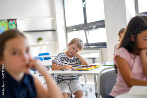 Slika na platnu Tired schoolboy struggling to stay awake during class