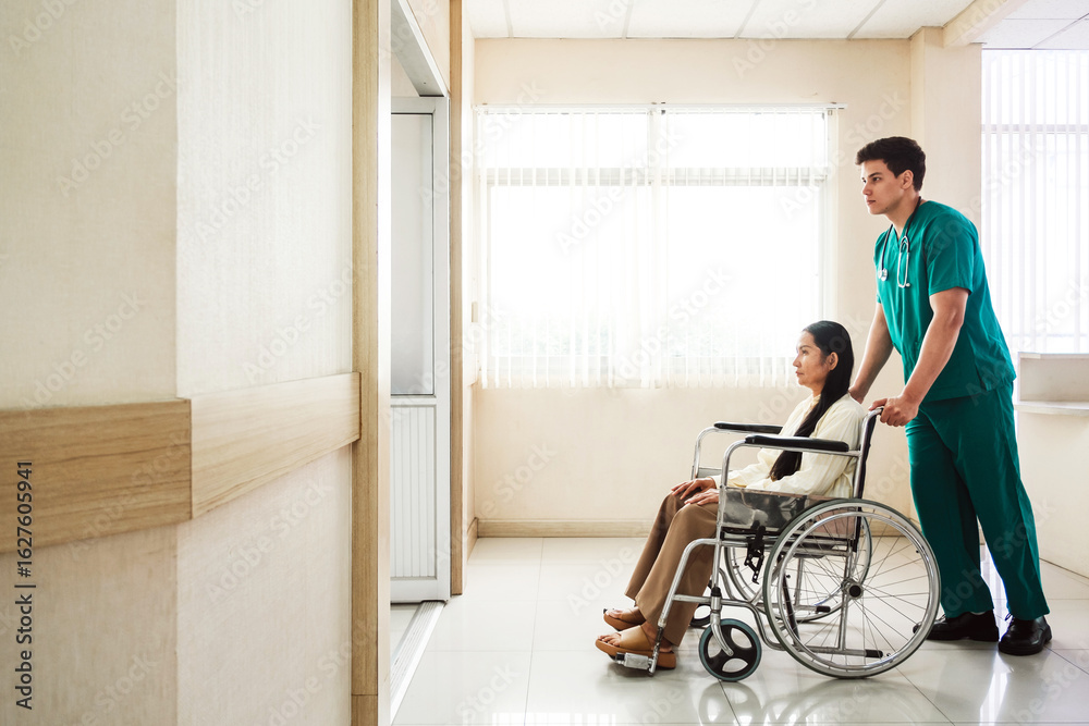 Male nurse in green scrubs assists female patient in a wheelchair along a bright hospital corridor, representing patient care, accessibility, and modern healthcare support in a clinical setting. Male nurse in green scrubs assists female patient in a wheelchair along a bright hospital corridor, representing patient care, accessibility, and modern healthcare support in a clinical setting.