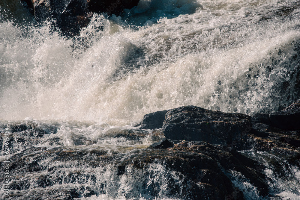 Obraz premium streams of clear waterfall water and stone banks of a mountain river