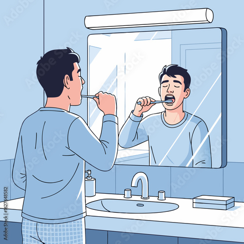 Young man in blue pajamas brushing his teeth while looking at his reflection in the bathroom mirror.