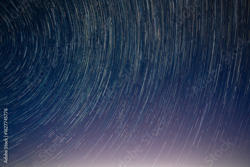 Long exposure photo of star trails spinning above the dark, peaceful skies of Bermuda