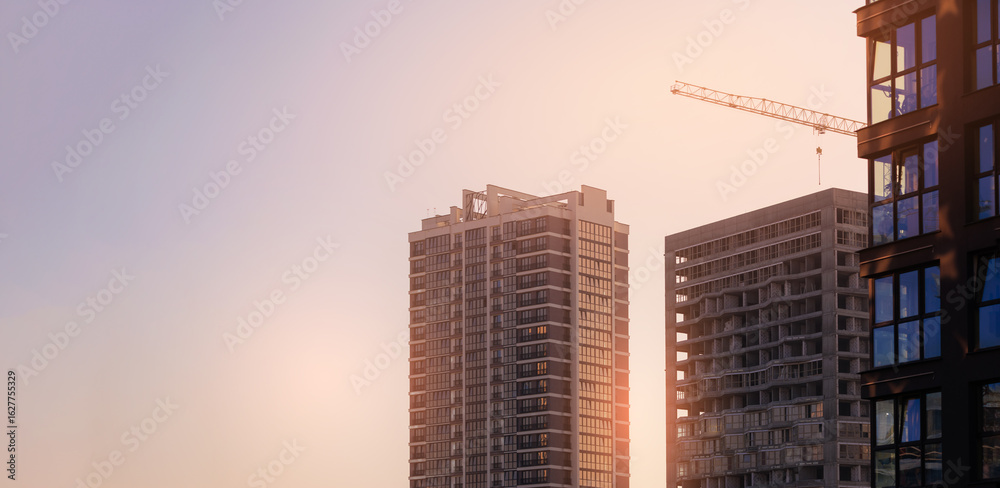 Fototapeta premium Construction of buildings and high-rise cranes against the sky
