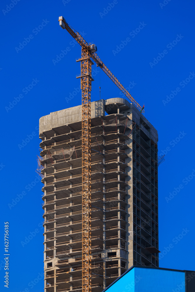 Fototapeta premium Construction of buildings and high-rise cranes against the blue sky