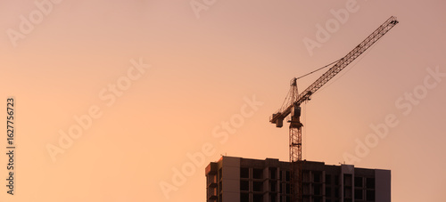 Construction of buildings and high-rise cranes against the evening sky