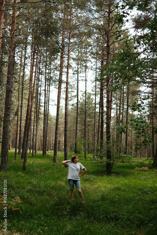 Woman standing among tall pine trees and green ferns in Tara National Park, Serbia. Peaceful summer forest scene with natural textures. Woman standing among tall pine trees and green ferns in Tara National Park, Serbia. Peaceful summer forest scene with natural textures.