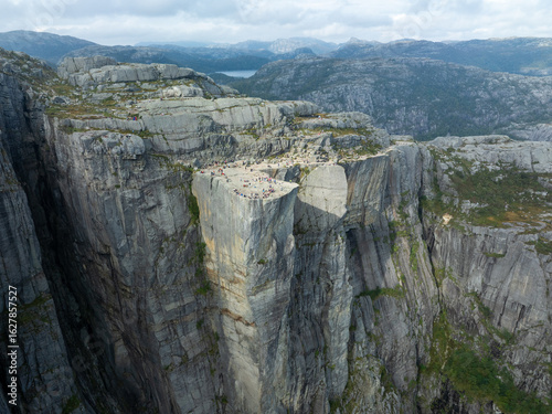Aerial view of the majestic Preikestolen cliff, a natural granite stage for eager onlookers against a backdrop of serene, rugged mountains, Stavanger, Norway.