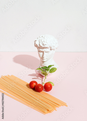 Basic ingredients for spaghetti with tomato sauce, inspired by popular Italian culture, composition on a pastel pink background.