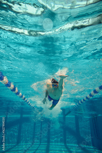 Cuadro en lienzo A competitive swimmer practices the freestyle stroke underwater in a clear blue pool lane