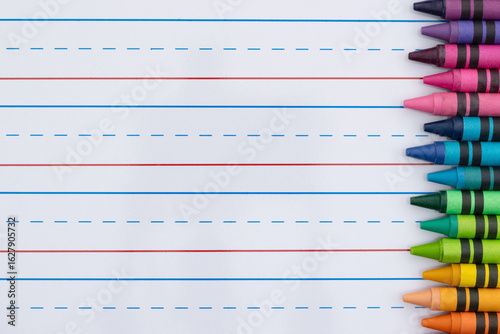 Crayons with ruled loose leaf notebook paper background