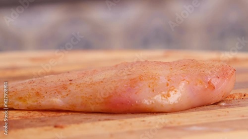 Cook seasoning a chicken breast with oils.