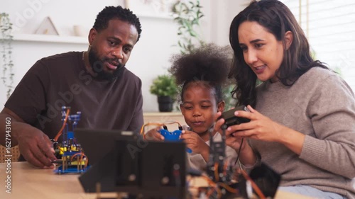 Parents and child assemble a diy robotics kit at home, learning stem skills through play; hands-on coding, engineering and problem solving, modern family education and teamwork.