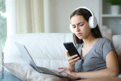 Tapety artystyczne Confused woman checking phone while is using laptop