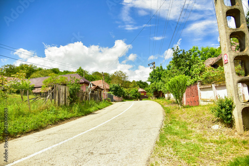 Calle de pueblo con coches y casas tradicionales. 