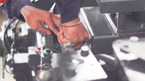 A mechanic is checking and inspecting the Komatsu D155 transmission trouble while testing the transmission on the test bench in the workshop.